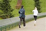 Man and woman running along pathway, rear view