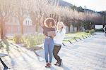 Two young female friends in park laughing at digital tablet, Como, Italy