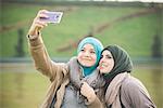Two female friends at lakeside posing for smartphone selfie