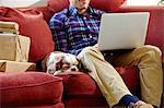 Mid adult man using laptop on sofa in picture framers showroom