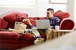 Mid adult man preparing parcels on sofa in picture framers showroom