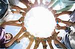 Team forming connected circle surrounding plastic hoop