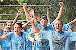 Enthusiastic team cheering in rain on boot camp obstacle course