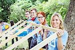 Portrait of smiling volunteers lifting construction frame