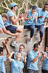 Team clapping and celebrating at wall on boot camp obstacle course