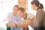 Business people stacking green blocks in sunny office