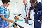 Doctors and nurse talking with patient on stretcher in hospital corridor