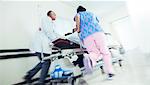 Doctor and nurse rushing patient on stretcher in hospital corridor