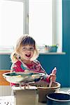 Smiling girl baking with mixing bowl in kitchen