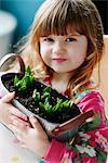 Close up portrait of girl holding sprouting flowers in basket