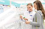 Pharmacist and customer reviewing label on bottle in pharmacy