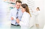 Pharmacist and customer reviewing prescription in pharmacy