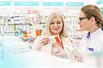 Pharmacist and customer reading label on box in pharmacy