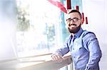 Portrait of smiling businessman with beard at laptop in cafe