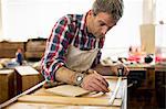 An antique furniture restorer measuring a piece of wood.