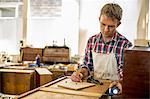 Antique furniture restorer using a pencil drawing and planning his work.