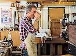 An antique furniture restorer in his workshop havng a coffee break.