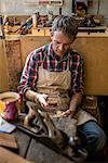 An antique furniture restorer in his workshop, using a smart phone.