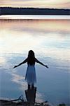 A woman in a white dress in shallow water at dusk