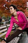 USA, New York, Manhattan, Greenwich Village, Young woman stretching on bench in park