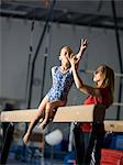 USA, Utah, Orem, coach assisting girl gymnast (10-11) on balance beam