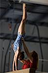 USA, Utah, Orem, coach assisting girl gymnast (10-11) on balance beam