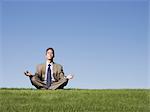 businessman meditating on the grass