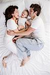 couple and baby lying on a bed