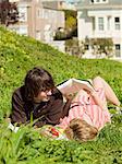 USA,California,San Francisco,Young couple lying on grass reading book