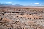 Chile, Cordillera de la Sal, Antofagasta Region, El Loa Province. A view looking across Moon Valley to the snow-capped Andes Mountains.  The oasis of San Pedro de Atacama is in the middle distance.