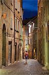 Man walking along street at dusk, Urbino (UNESCO World Heritage Site), Le Marche, Italy