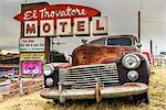 Old rusted Pontiac car and vintage motel sign behind along the historic U.S. Route 66, Kingman, Arizona, USA