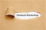 The text Content Marketing appearing behind torn brown paper.