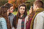 Crying teen in scarf with sympathetic friends outdoors