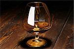 Luxury still life with glass of cognac with refllection of light on a wood background. Front view with copyspace. Close up shot