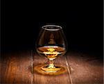 Luxury still life with glass of cognac, on a wood background. Front view with copyspace. Close up shot.