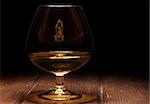 Luxury still life with glass of cognac, on a wood background. Front view with copyspace. Close up shot. High resolution