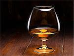 Luxury still life with glass of cognac, on a wood background. Front view with copyspace. Close up shot