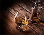 Luxury still life with glass of cognac, and bottle on a wood background. Top view with copyspace. High resolution