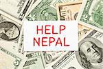 Help Nepal written on white card with US dollar bills as a background.