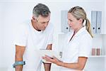 Doctor showing clipboard to her patient with crutch in medical office