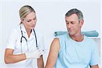 Doctor doing an injection to her patient in medical office