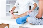 Doctor examining her patient leg in medical office