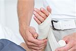 Doctor bandaging his patient hand in medical office