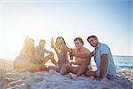 Happy hipsters relaxing and drinking beer at the beach