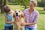 Mother and her daughter with their dog in the park on a sunny day