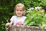 Girl gardening, carrying flowers in basket