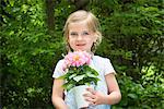 Girl gardening, holding pot with flowers