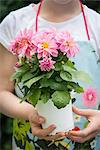 Girl holding pot with flowers in hands