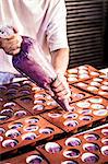 Confectioner working with icing bag in bakery